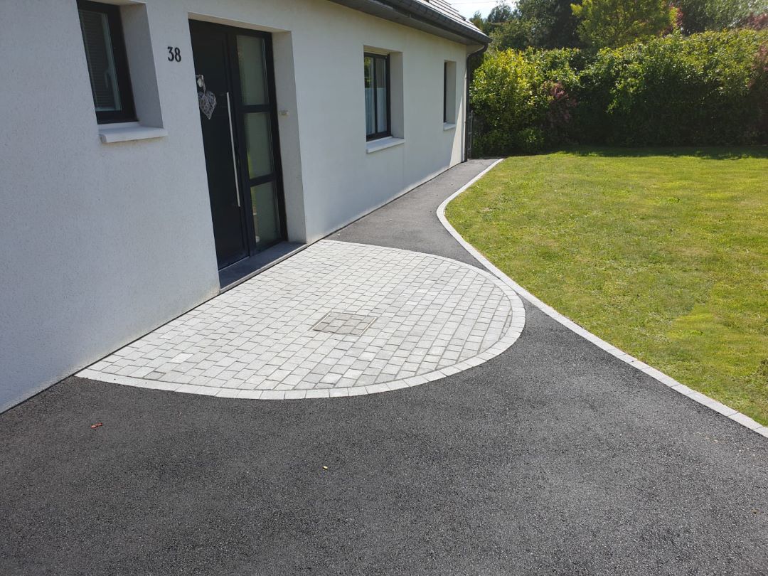 Allée de jardin aménagée avec sol en enrobé noir et pavés à Gestel